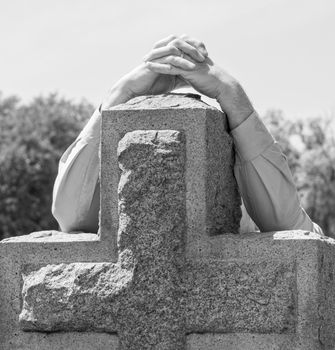 Black and white lone figure of person's hands grieving at cemetery