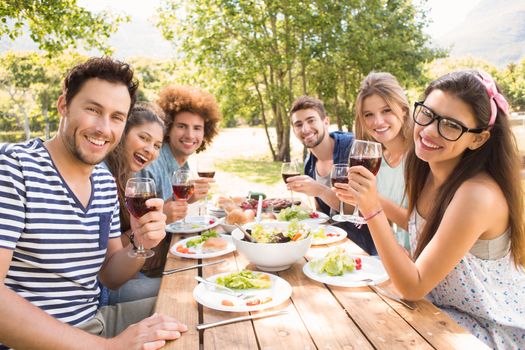 Happy friends in the park having lunch on a sunny day