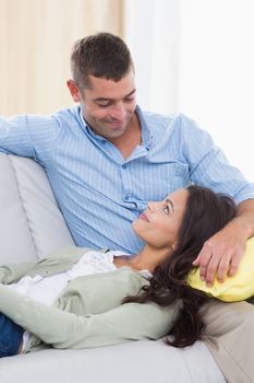 Romantic couple looking at each other while sitting on sofa at home