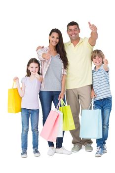 Portrait of happy family with shopping bags gesturing thumbs up over white background