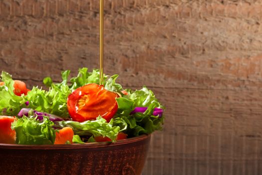 Fresh green  organic salade on wooden background. A thin stream of olive oil pouring into salad