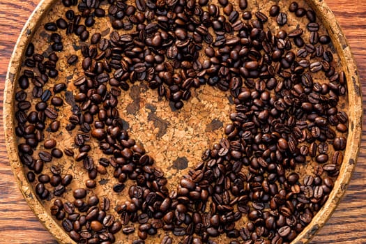 Heart shape made from coffee beans on a plate made of natural cork
