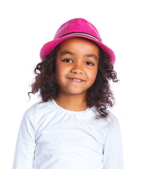 Closeup portrait of a pretty mulatto girl in pink hat smiling at camera on white background