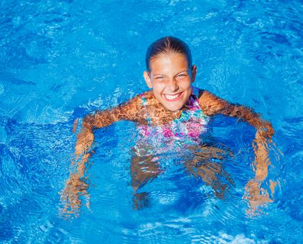 Cute happy young girl swimming and snorking in the swimming pool