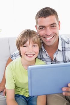Portrait of happy father and son with digital tablet at home