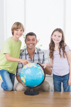 Portrait of father with son and daughter exploring map on globe at home