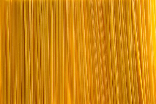 Full frame background texture and pattern of dried uncooked fettuccine pasta for a food or Italian themed concept