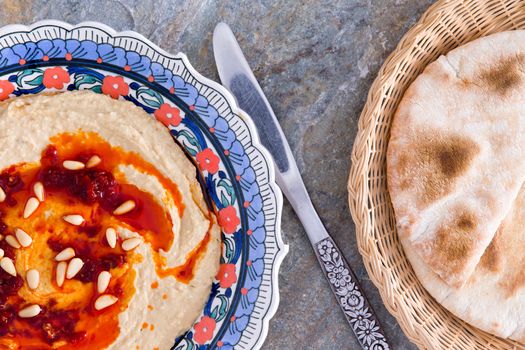 Hummus dip, a nutritious blend of chickpeas, tahini, oil, lemon juice, and garlic, with freshly baked pita bread in a basket, view from above