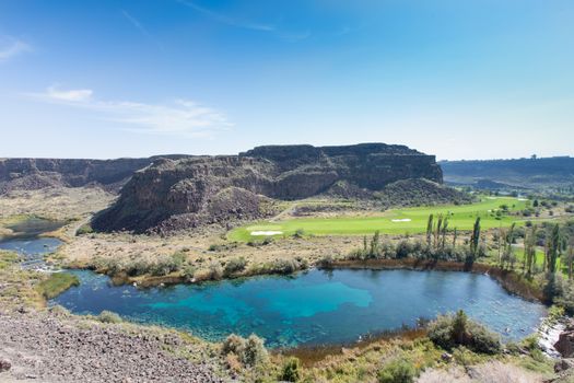 Warm springs and tranquil blue lake, Jerome, Idaho with lush green farmland in the valley between rugged mountain peaks in a scenic view of the countryside