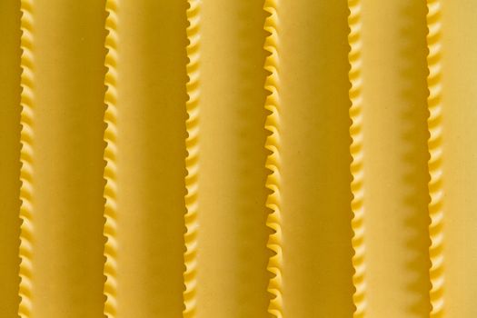 Organic dried durum wheat semolina lasagne background texture with a decorative parallel pattern formed by the crimped edges of the sheets