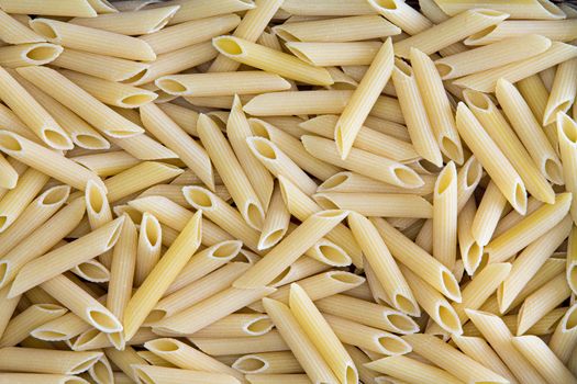 Background texture of penne, rigate or ziti pasta with its hollow diagonally cut tubes used in Italian cuisine and for a tasty ziti casserole with cheese