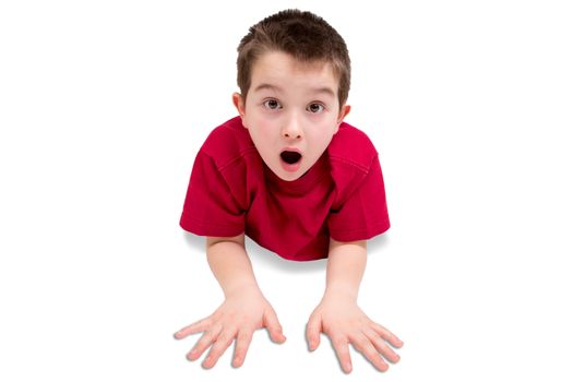 Surprised Cute Male Kid, Wearing Casual Red Shirt, Lying on his Stomach While Looking at the Camera. Isolated on White Background.