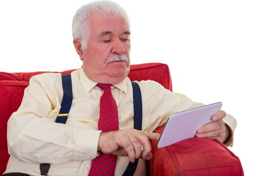 Close up Updated Old Gentleman Using his Tablet Computer Seriously White Sitting on a Chair on a White Background.