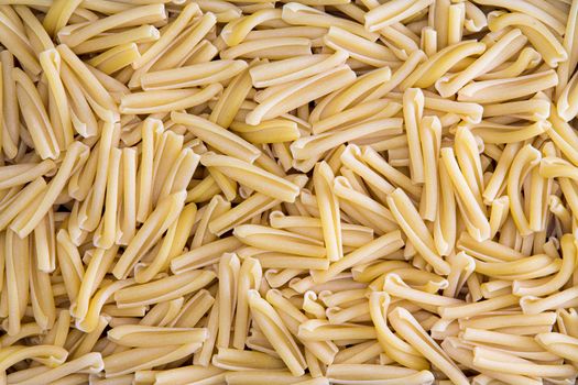 Background texture of dried Italian casarecce, a tubular regional pasta from the island of Sicily made from durum wheat dough used in maccaroni dishes