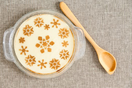 Aerial Shot of a Gourmet Tasty Milky Semolina Dessert on Bowl Placed on Top of a Gray Cloth with Wooden Ladle on Side.