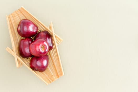 Healthy Fresh Red Apples on a Wooden Tray Placed on Top of a Light Green Table, Emphasizing Copy Space. Captured in High Angle View.