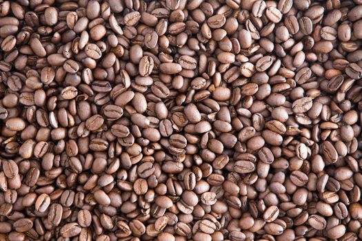 Background texture of roasted brown coffee beans ready for grinding for a fresh cup of aromatic coffee at breakfast, close up view from above