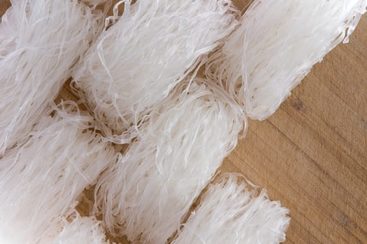 Overhead view of several rolls of dried mung bean vermicelli noodles, or cellophane noodles, rich in protein and gluten free arranged on a wooden table