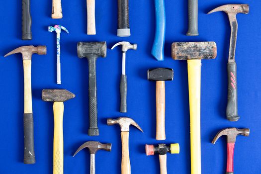 World of hammers with a large assortment of different shapes arranged neatly in vertical lines on a bright blue background in a DIY, carpentry, building, maintenance and renovation concept