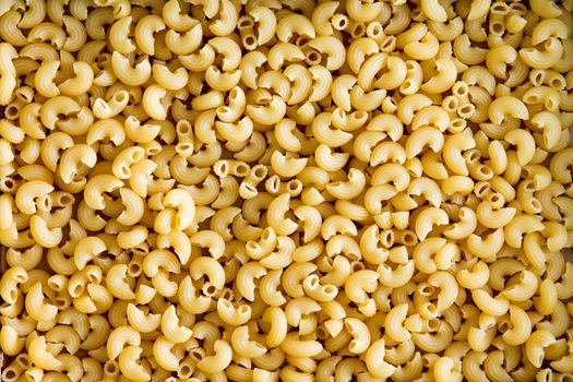 Background texture of healthy gluten free elbow pasta for use in Italian cuisine for people suffering from gluten intolerance