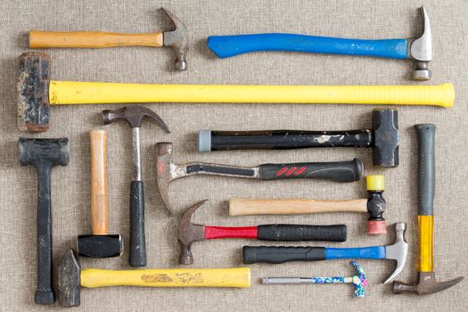 Large selection of different hammers and mallets arranged on a neutral beige background viewed from above in a DIY, renovation, maintenance,and construction concept