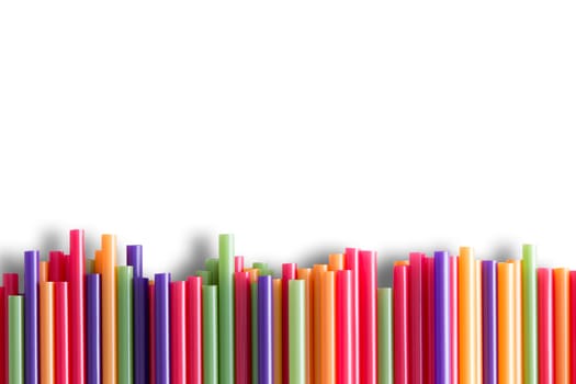 Rainbow colored plastic drinking straws background pattern arranged as a line border at the bottom of the frame with copyspace over white