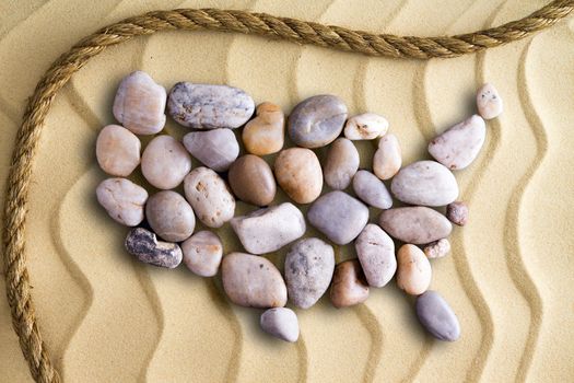 Pebbles arranged in the shape of a map of the United Sates of America on decorative beach sand with wavy lines in an undulating pattern with a rope border in a nautical theme