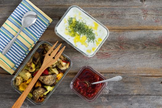 Healthy meal of roasted or grilled assorted vegetables including sweet pepper, eggplant and zucchini served with tzatziki or Turkish cacik with yogurt and dill and a pepper paste on an old wood table