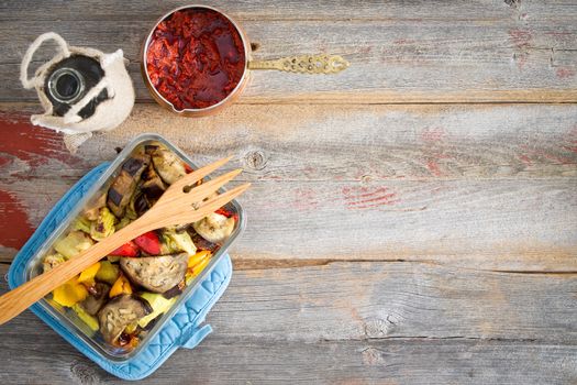 Healthy roast Turkish style vegetables served with a red hot pungent pepper paste and olive oil on a rustic wooden table with copyspace