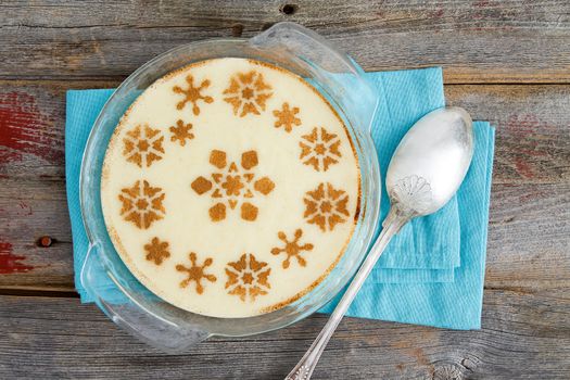 High Angle View of Gourmet Semolina Dessert with Milk Served on a Glass Bowl on Top of a Rustic Wooden Table with Napkin and Spoon.