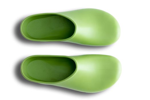 Pair of clean green simple clog form rubber gardening shoes neatly arranged side by side over a white background, overhead view