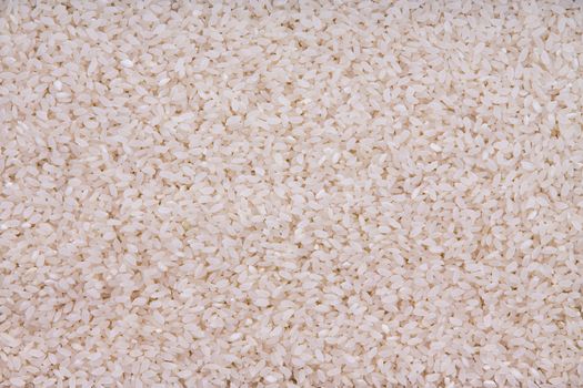 Background texture of long-grain parboiled rice grains which have been hulled and partially cooked to speed up cooking time, a staple cereal and starch