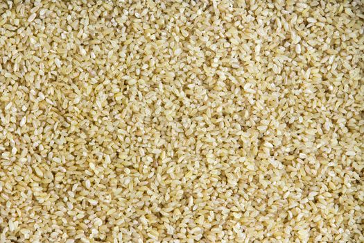 Background texture of wholesome dried cracked or crushed wheat a staple cereal and grain used to speed up the cooking process, full frame overhead view