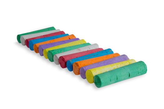 Neatly aligned diagonal row of colored chalks in the colors of the spectrum or rainbow ready for little children to pick up on a white background with copyspace