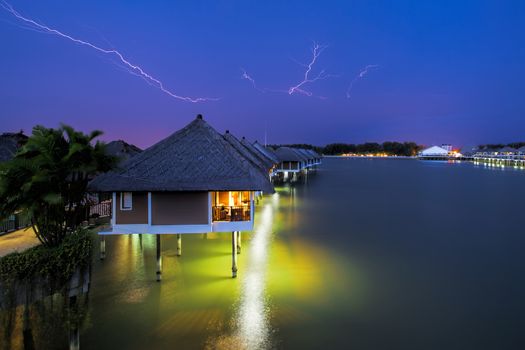 Lightning colouring the sky over waters villas at night