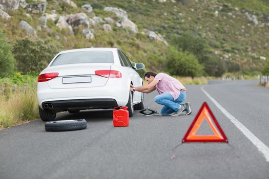 Man changing wheel after a car breakdown at the side of the road