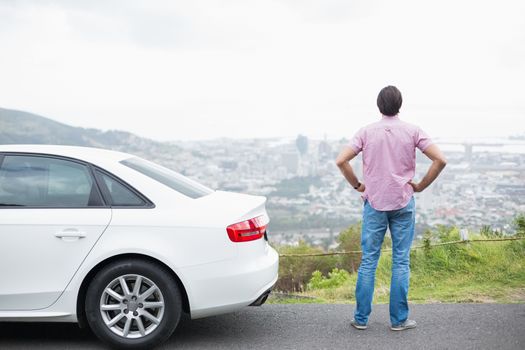 Man looking at the view near his car at the side of the road