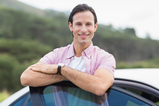 Man smiling at camera outside his car