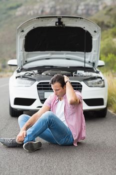 Stressed man sitting after a car breakdown at the side of the road