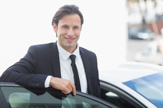 Businessman smiling at camera outside his car