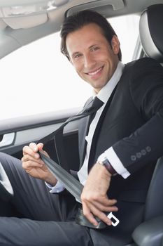 Businessman putting on his seat belt in his car