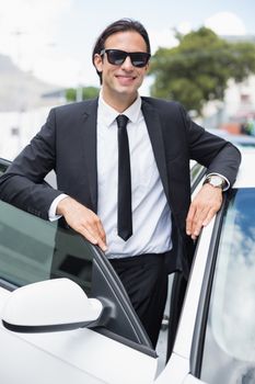 Businessman leaning on the door of his car