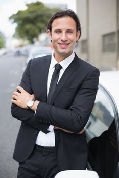 Businessman leaning on the door of his car