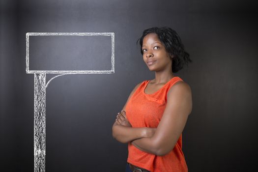 South African or African American woman teacher or student with chalk road advertising sign blackboard background