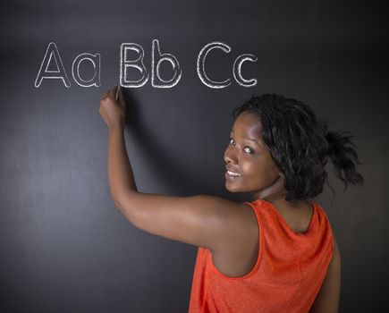 South African or African American woman teacher or student learn alphabet write writing on chalk blackboard background