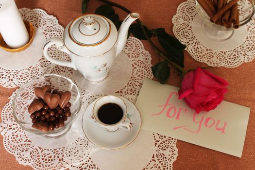 Still Life with cup of coffee, coffee pot, vase with sweets and rose on lace salfete