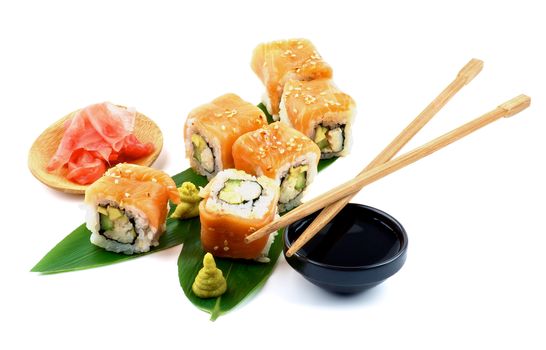 Arrangement of Maki Sushi with Salmon, Crab, Avocado and Cheese on Green Palm Leafs with Soy Sauce, Ginger and Pair of Chopsticks isolated on white background