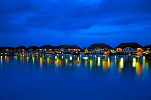 Water villas making reflections in the ocean at sunset
