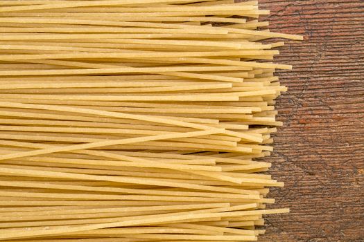 uncooked gluten free, brown rice pasta, spaghetti style on a rustic wood table