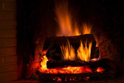 Burning fireplace with firewood and glowing ashes